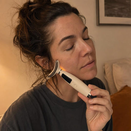 Woman pressing the warm Solace Pro 1 to her jaw muscle in a dim evening bedroom